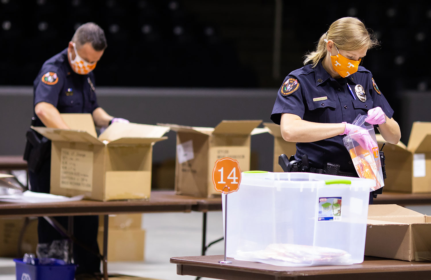 Two uniformed UTPD officers are stuffing health kits during COVID